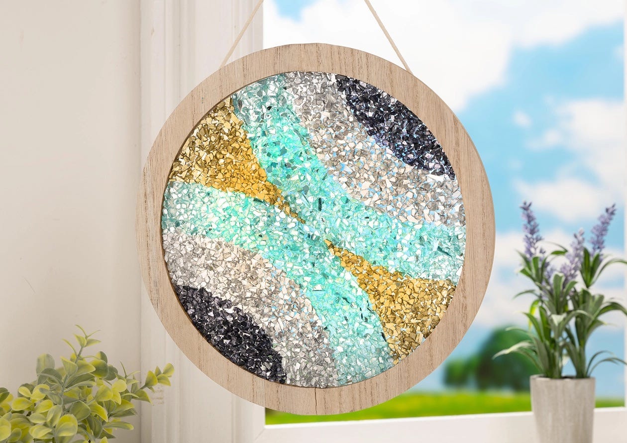 Round wood-framed wall art made with Fragment Effects glass chips in gold, silver, black, and teal mosaic patterns.