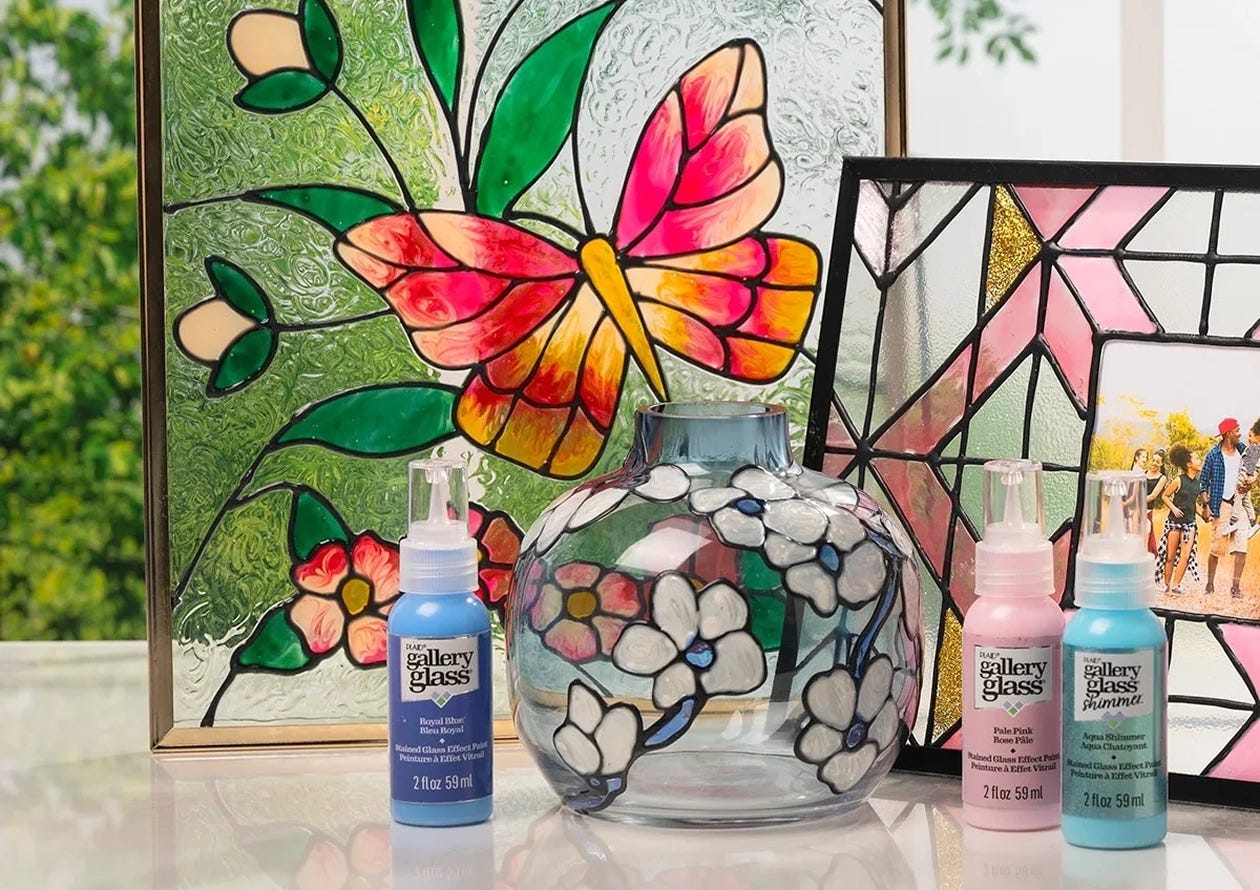 Gallery Glass-painted decor, including a butterfly window panel, floral vase, and stained-glass-style photo frame with paint bottles.