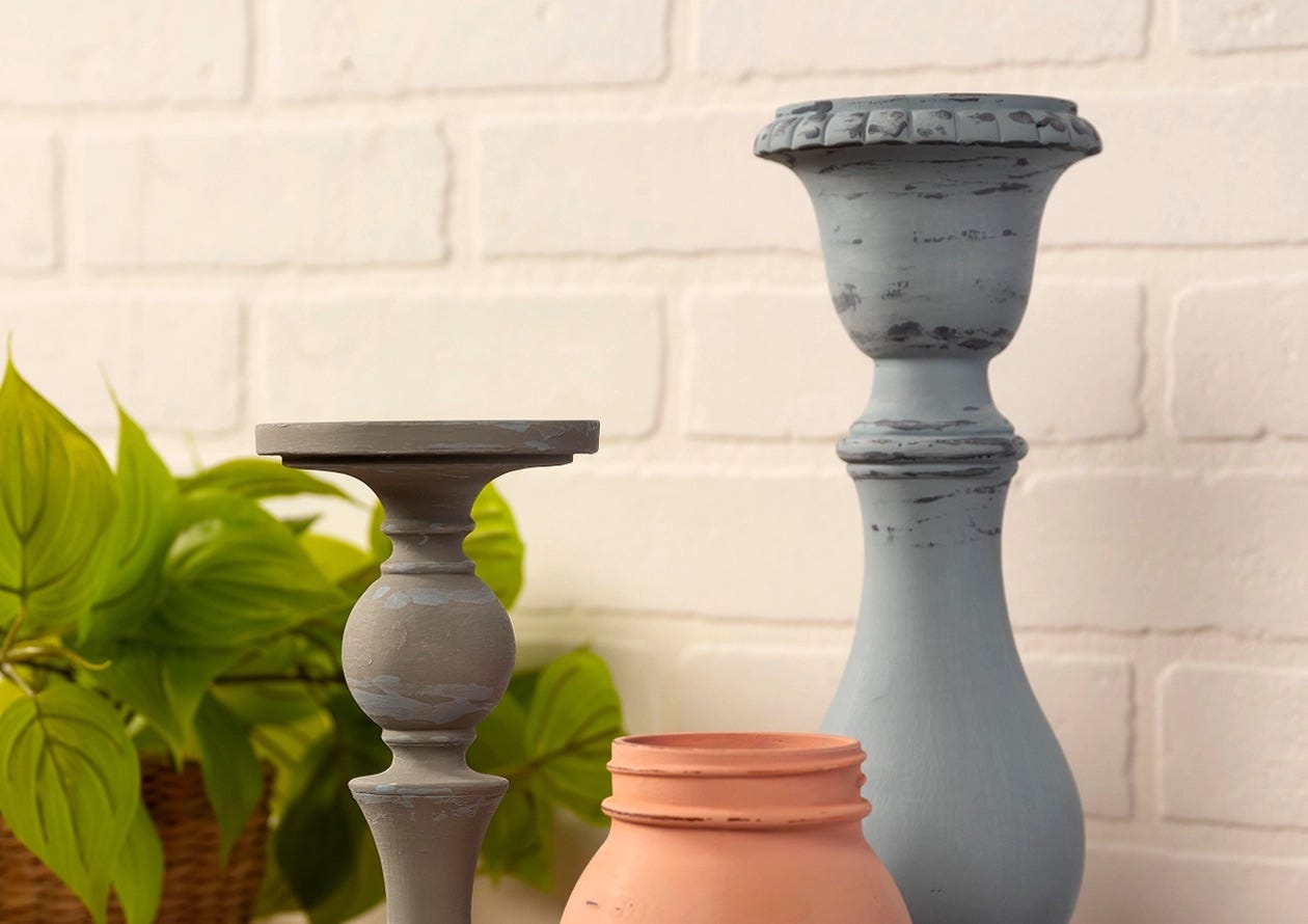 Waverly Inspirations-painted candle holders and a jar with a distressed, chalky finish in muted gray, blue, and peach tones.