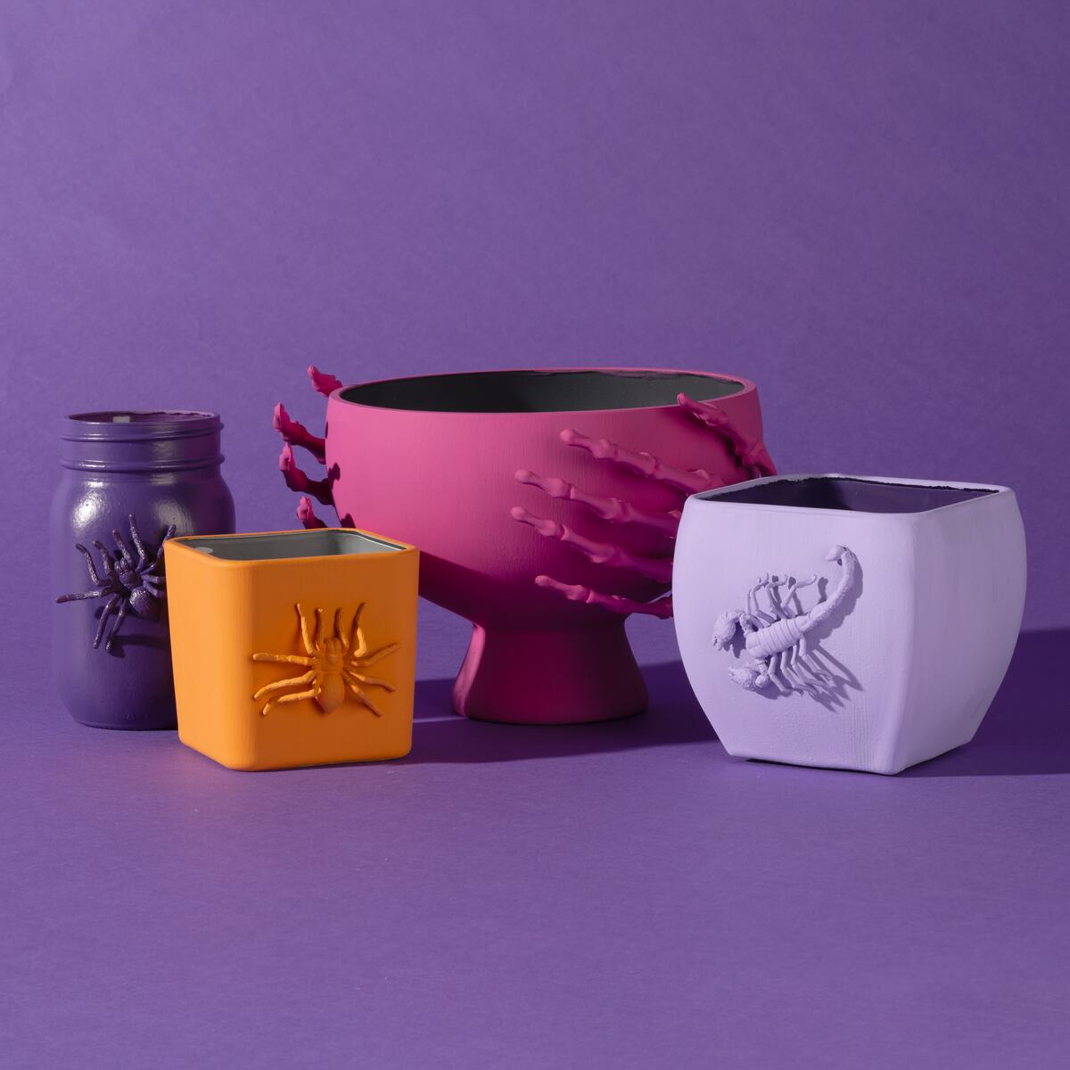 Brightly painted Halloween candy bowls with spooky critters and skeleton hands