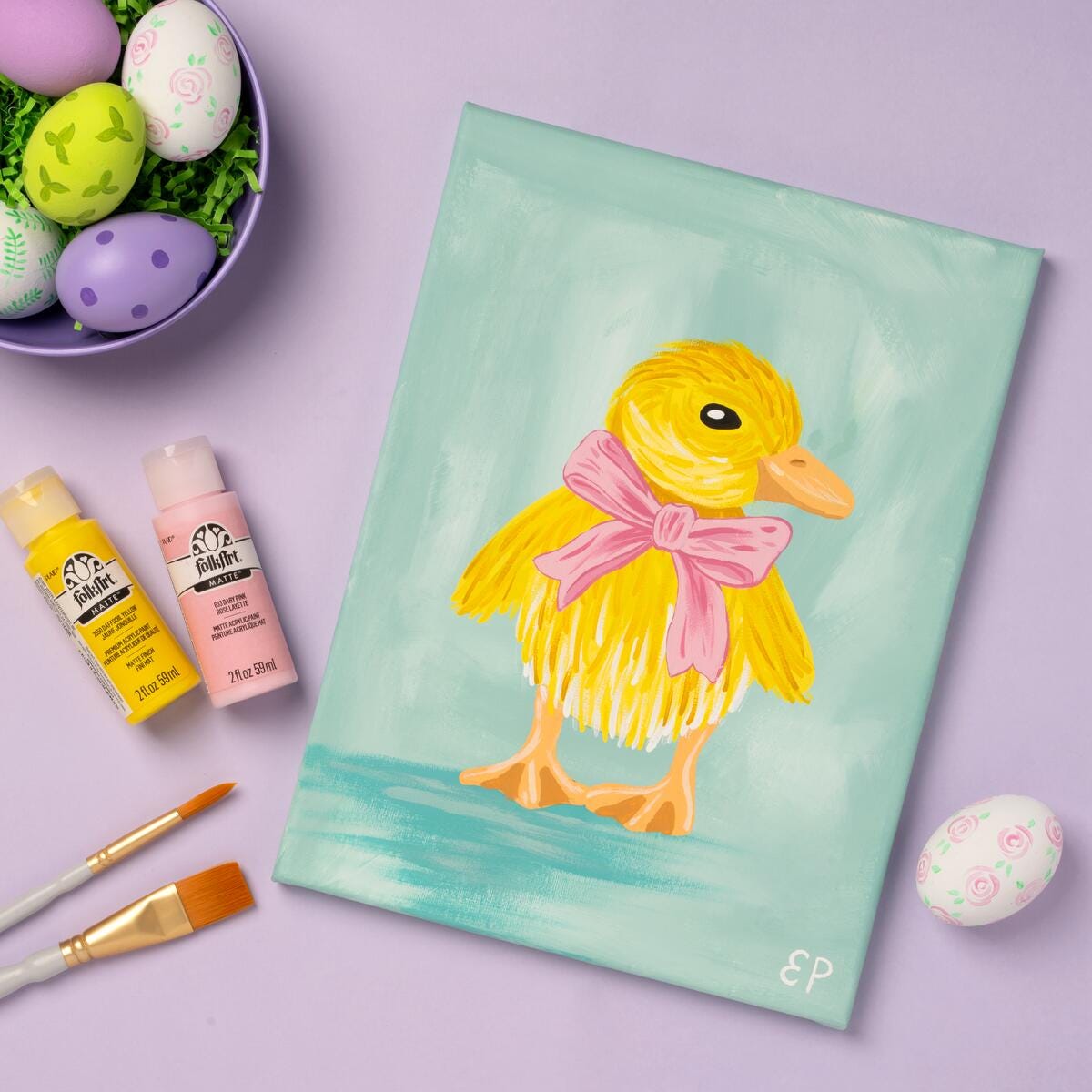 A painting of a yellow baby duck on cavas with FolkArt Paints and Easter eggs