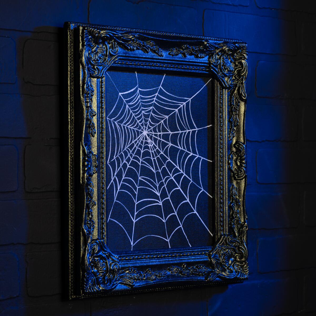 Glow-in-the-dark painting of a spider web in a painted antique frame