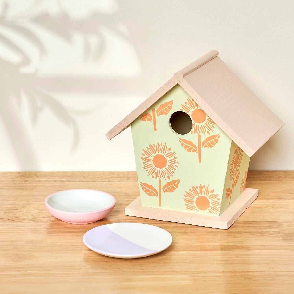 A small wooden birdhouse and smal trinket plates painted with colors from the Martha Stewart Hushed Hues set