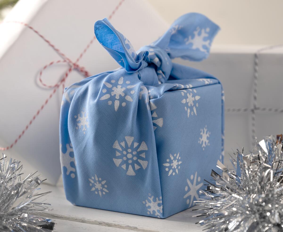 Presents wrapped in fabric gift wrap with stenciled snowflakes 