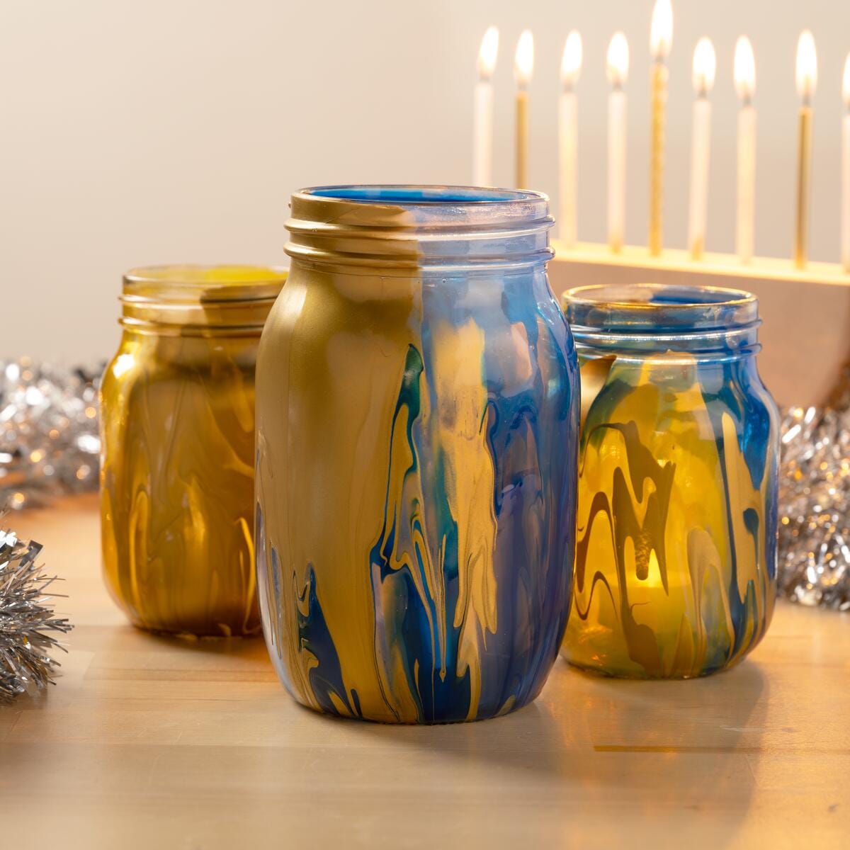 Mason jars painted in a swirl of blue and gold with little tea lights inside